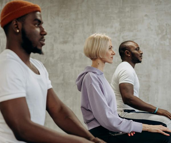 A diverse group of people sitting peacefully in a bright yoga studio.
